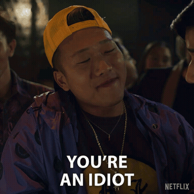 A Man Wearing A Yellow Hat And A Purple Jacket Says " You 'Re An Idiot " GIF