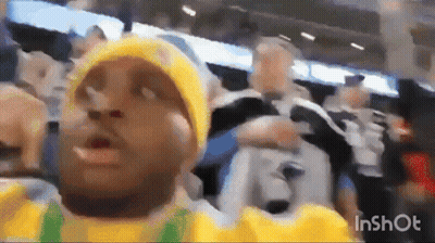 A Man Wearing A Yellow Hat And A Yellow Shirt Is Standing In Front Of A Crowd . GIF