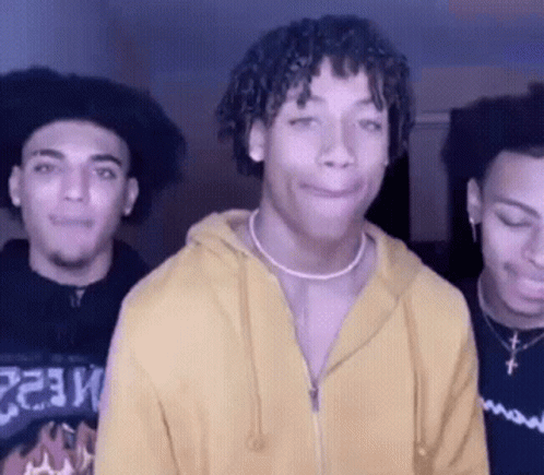 A Man Wearing A Yellow Hoodie Is Standing With Two Other Men GIF