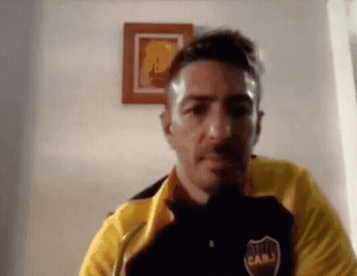 A Man Wearing A Yellow Jacket And A Black Shirt With The Word Cabj On It Is Looking At The Camera . GIF