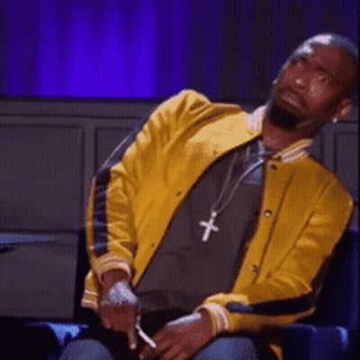 A Man Wearing A Yellow Jacket And A Necklace With A Cross On It GIF