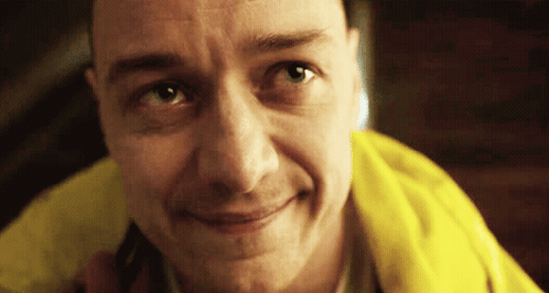 A Man Wearing A Yellow Jacket Is Smiling And Looking At The Camera GIF