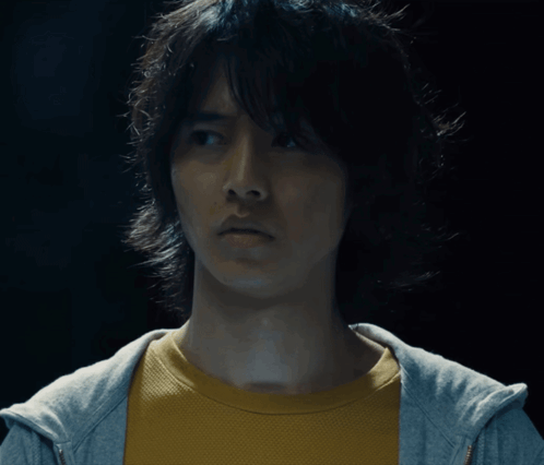 A Man Wearing A Yellow Shirt And A Gray Hoodie Looks At The Camera GIF