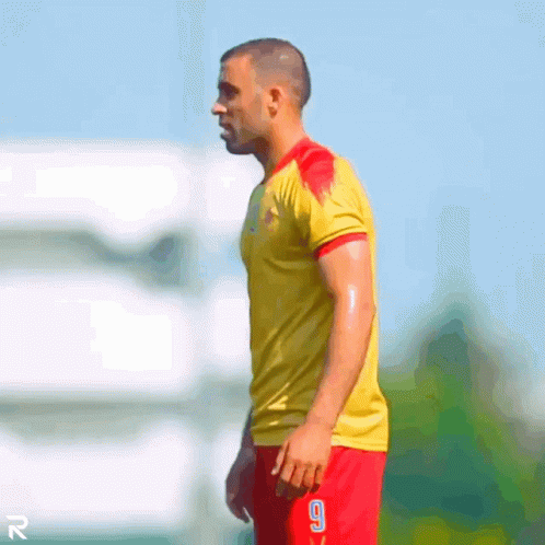 A Man Wearing A Yellow Shirt And Red Shorts With The Number 9 On The Shorts GIF