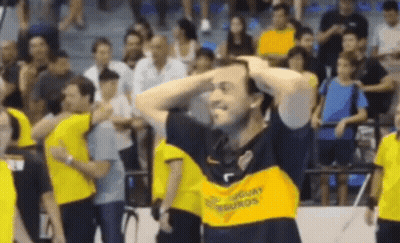 A Man Wearing A Yellow Shirt That Says Uruguay On It Is Holding His Head . GIF