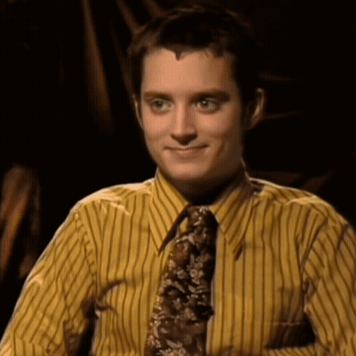 A Man Wearing A Yellow Striped Shirt And Tie Smiles For The Camera GIF