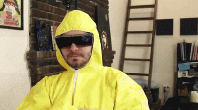 A Man Wearing A Yellow Suit And Sunglasses Is Standing In Front Of A Fireplace GIF