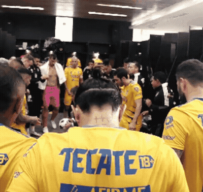 A Man Wearing A Yellow Tecate Jersey Is Surrounded By Other Men GIF