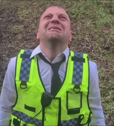 A Man Wearing A Yellow Vest And Tie Looks Up At Something GIF