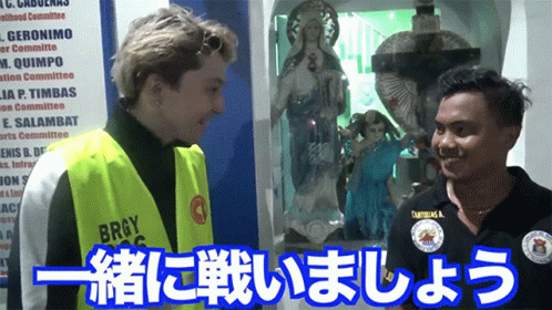 A Man Wearing A Yellow Vest That Says Brgy Is Talking To Another Man GIF