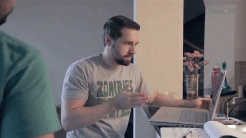 A Man Wearing A Zombie T-Shirt Is Using A Laptop Computer GIF