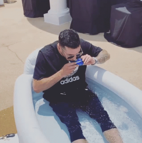 A Man Wearing An Adidas Shirt Sits In A Pool Of Water GIF