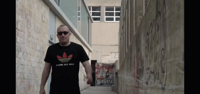 A Man Wearing An Adidas T-Shirt Walks Down A Street GIF
