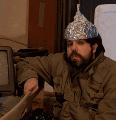 A Man Wearing An Aluminum Foil Hat Is Sitting In Front Of A Computer GIF