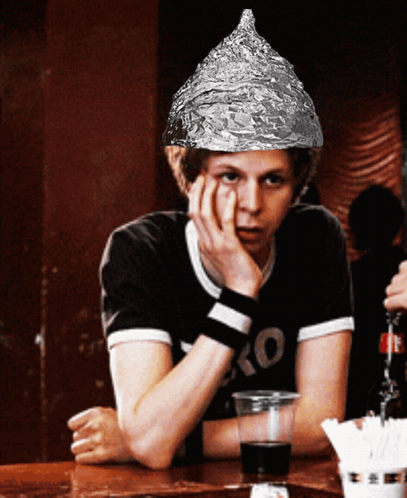 A Man Wearing An Aluminum Foil Hat Sits At A Bar GIF