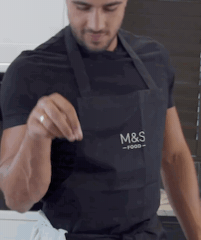 A Man Wearing An Apron That Says M & S Food On It GIF