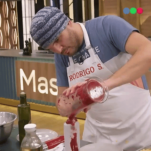 A Man Wearing An Apron That Says Rodrigo S. Pours Liquid Into A Bottle GIF