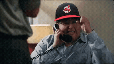 A Man Wearing An Indians Hat Is Talking On A Telephone GIF