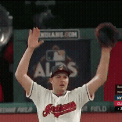 A Man Wearing An Indians Jersey Is Raising His Hands In The Air GIF