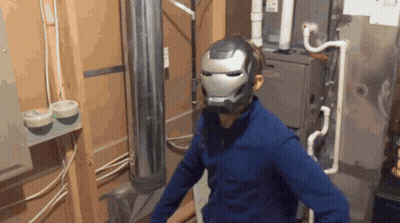 A Man Wearing An Iron Man Helmet Is Standing In A Room GIF