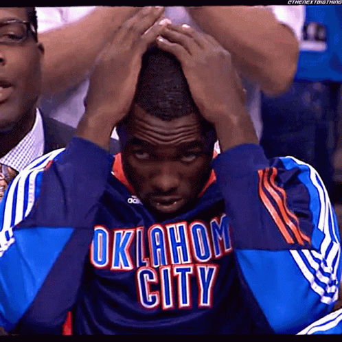 A Man Wearing An Oklahoma City Jersey Is Holding His Head GIF
