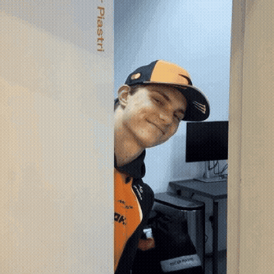 A Man Wearing An Orange And Black Hat Is Peeking Out From Behind A Wall That Says Piastri On It GIF