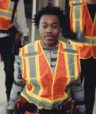 A Man Wearing An Orange And Yellow Safety Vest With The Letter T On It GIF