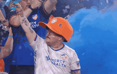 A Man Wearing An Orange Hat And A Mercy Health Shirt GIF