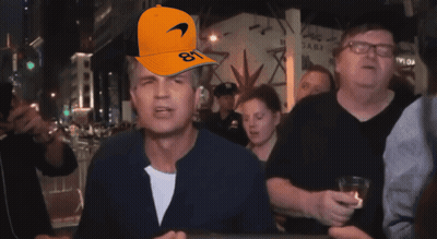 A Man Wearing An Orange Mclaren Hat With The Number 81 On It GIF