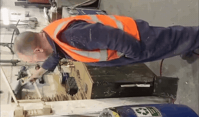 A Man Wearing An Orange Safety Vest Is Working On A Machine . GIF