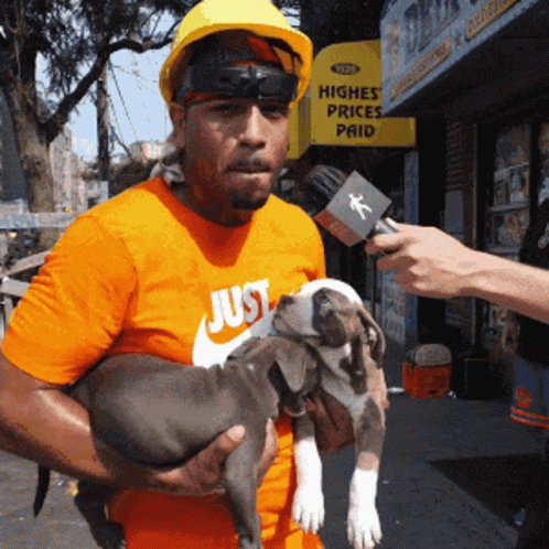 A Man Wearing An Orange Shirt That Says Just Is Holding A Puppy GIF