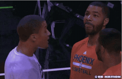 A Man Wearing An Orange Shirt That Says Phoenix Basketball Is Talking To Another Man GIF