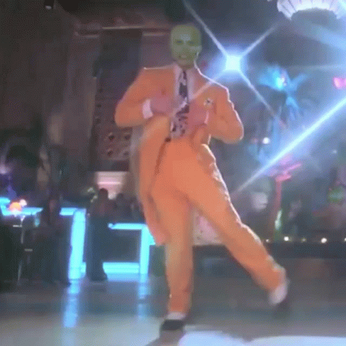Man In Orange Suit And Green Mask Dancing GIF