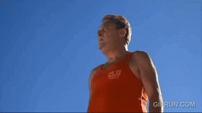 A Man Wearing An Orange Tank Top That Says C.l.u. On It GIF