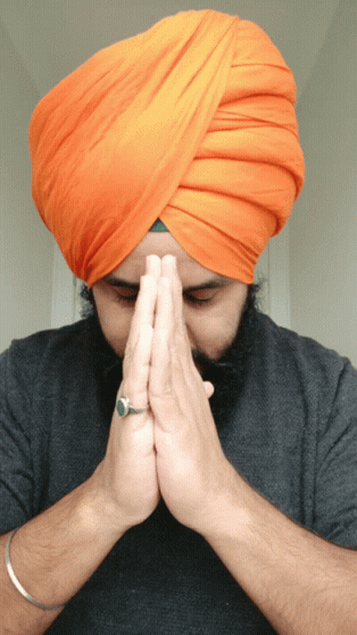 A Man Wearing An Orange Turban And A Ring On His Finger Prays GIF