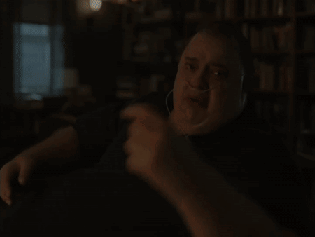 A Man Wearing An Oxygen Mask Is Sitting At A Table In Front Of A Bookshelf GIF
