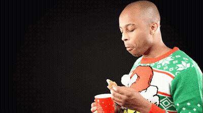 A Man Wearing An Ugly Christmas Sweater Is Holding A Cup Of Coffee GIF