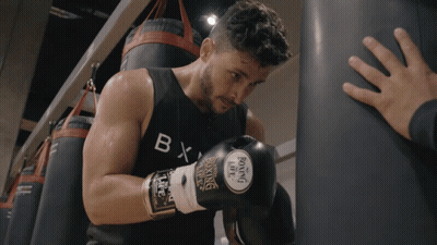 A Man Wearing Boxing Gloves And A Black Tank Top With The Letter B On It GIF