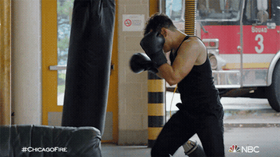 A Man Wearing Boxing Gloves Is Practicing In Front Of A Fire Truck With The Number 3 On It GIF