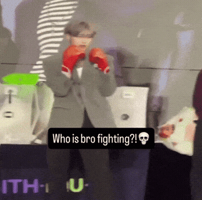 A Man Wearing Boxing Gloves Stands In Front Of A Sign That Says " Who Is Bro Fighting " GIF