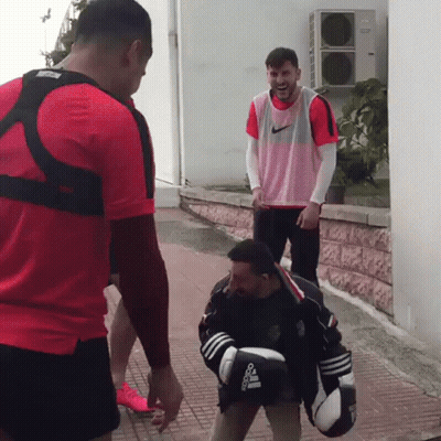 A Man Wearing Boxing Gloves That Say Adidas Is Standing Next To Another Man GIF