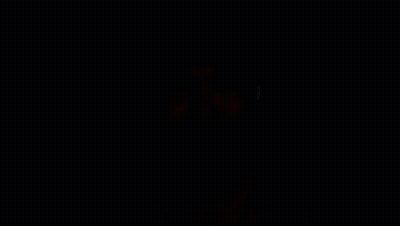 A Man Wearing Ear Buds Is Looking At The Camera In The Dark GIF