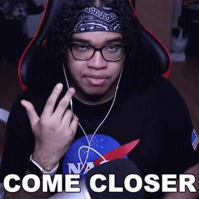a man wearing glasses and a bandana says come closer in front of a microphone