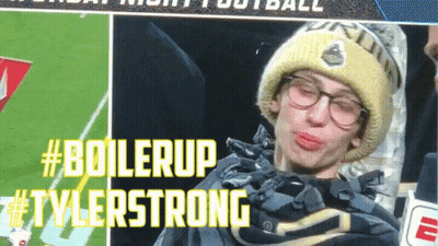 A Man Wearing Glasses And A Beanie Is Making A Funny Face With #Boilerup Tylerstrong Written In Yellow Letters GIF