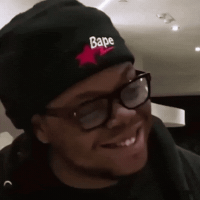 A Man Wearing Glasses And A Black Beanie With The Word Bape On It GIF