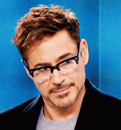 A Man Wearing Glasses And A Black Jacket Is Smiling GIF