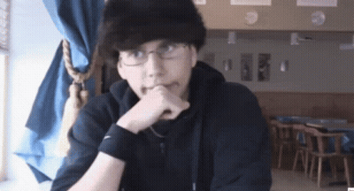 A Man Wearing Glasses And A Black Nike Wristband Is Sitting At A Table GIF