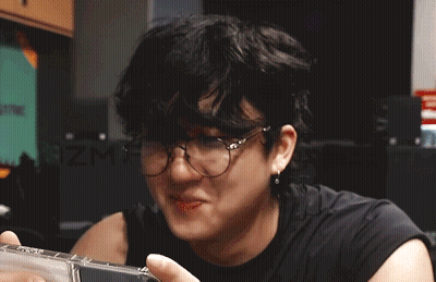 A Man Wearing Glasses And A Black Shirt Is Holding A Cd GIF