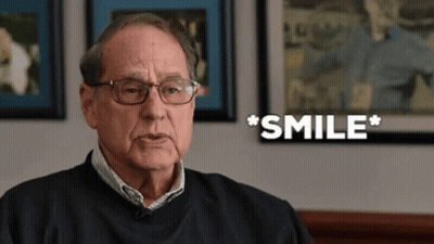 A Man Wearing Glasses And A Black Shirt Is Smiling GIF