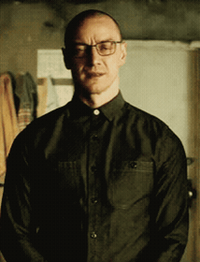 A Man Wearing Glasses And A Black Shirt Is Standing In A Room GIF